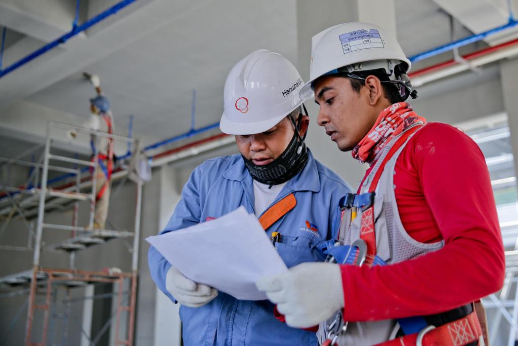 Two construction workers review a blueprint - BAM Group (construction project advisory) (industries)